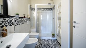 A bathroom with a white sink, toilet, and shower. The floor has a black and white patterned tile. - Scena Illustrata-Redi 51-un to 10 people (Florence)