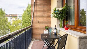 A balcony with a table and chairs, a potted plant, and a window with flowers. - Scena Illustrata-Redi 51-un to 10 people (Florence)