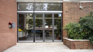A building entrance with glass doors, a mailbox, and a brick planter with plants. - Illustrated Scene-Redi 51-un to 10 people (Florence)