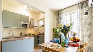 A modern kitchen with a central island, a dining table with chairs, and a window with curtains. - Illustrated Scene-Redi 51-un to 10 people (Florence)