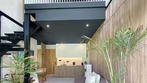 Ein modernes Interieur mit Küche, Essbereich und Sitzgelegenheit, inklusive Treppe und Zimmerpflanzen.