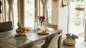 Uma mesa de jantar com uma fruteira, um vaso de flores e uma xícara.