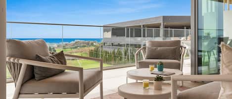 A balcony with a view of the sea, furnished with two sofas and a small table.