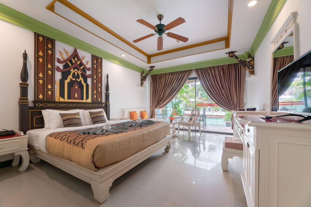 Ein geräumiges Schlafzimmer mit einem großen Bett, einem Deckenventilator, einem Fernseher und einem Balkon mit Aussicht.