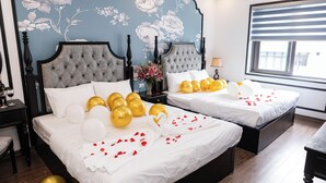 A double bed with white linens, gold and white balloons, and rose petals. - Royal Lotus Villa (Hanoi)