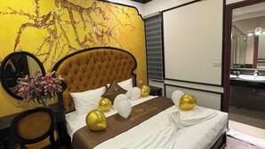 A hotel room with a large bed, a headboard, a bedside table with a vase of flowers, and a mirror. - Royal Lotus Villa (Hanoi)