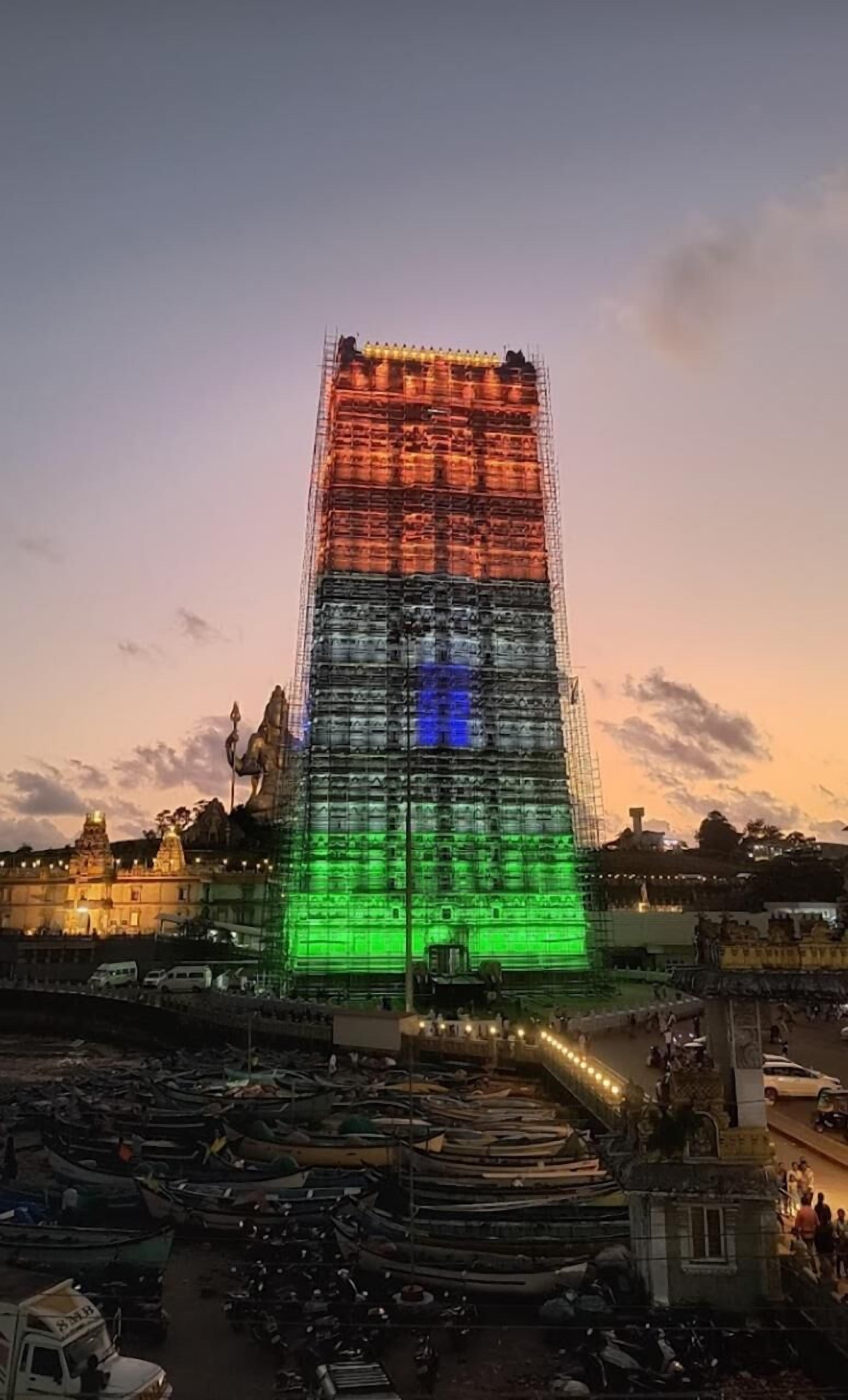 Un grande edificio in costruzione con impalcature, circondato da barche e veicoli parcheggiati.