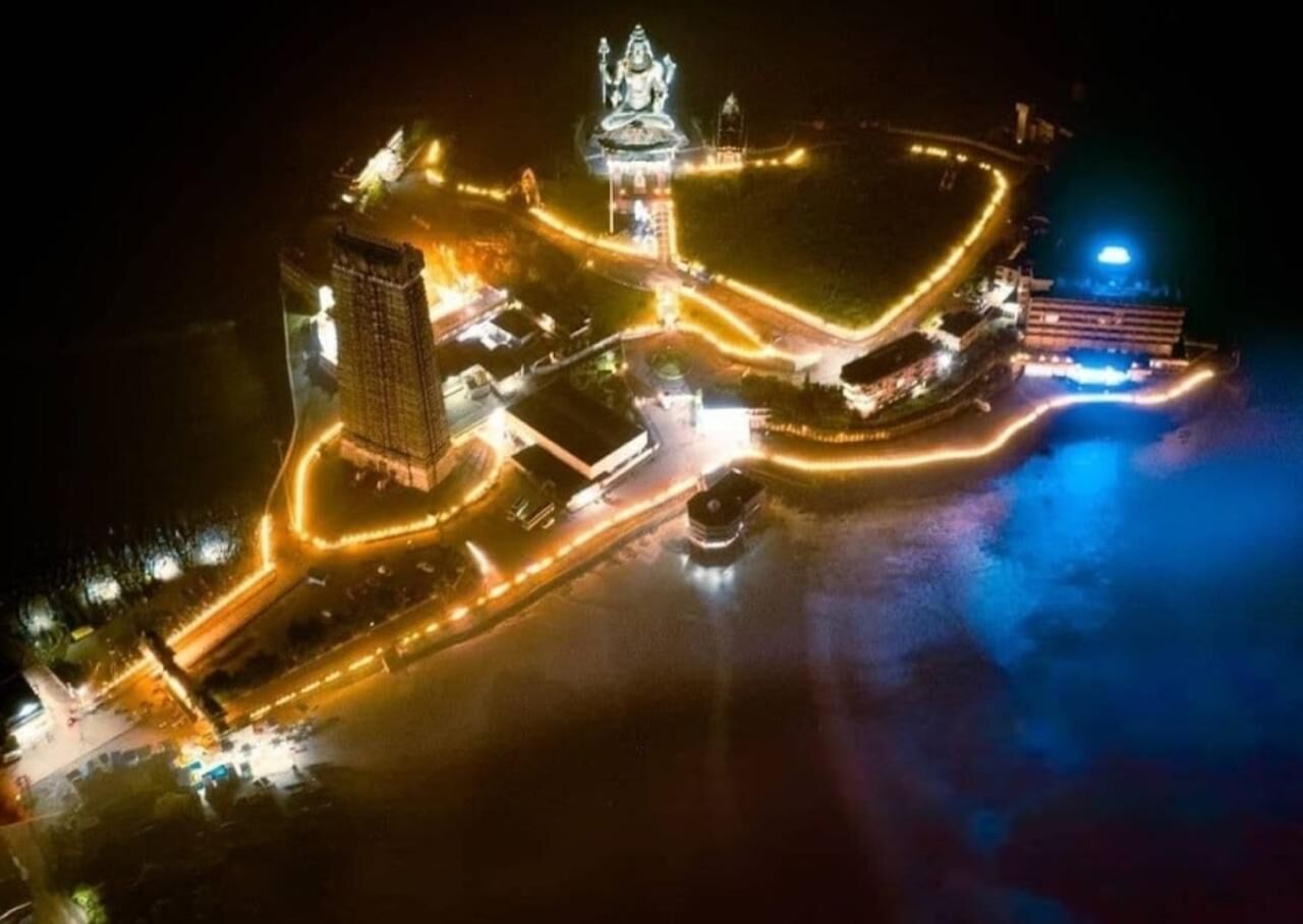 Une vue aérienne d’une zone bien éclairée, avec une statue imposante, un grand bâtiment et un tracé routier circulaire.
