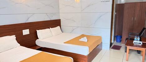 Habitación de hotel con dos camas, cabecero de madera, pared de mármol, equipo de aire acondicionado, escritorio con silla y armario.