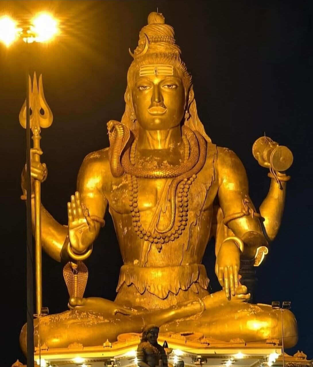 A large golden statue of a deity with multiple arms, a trident, and a drum.
