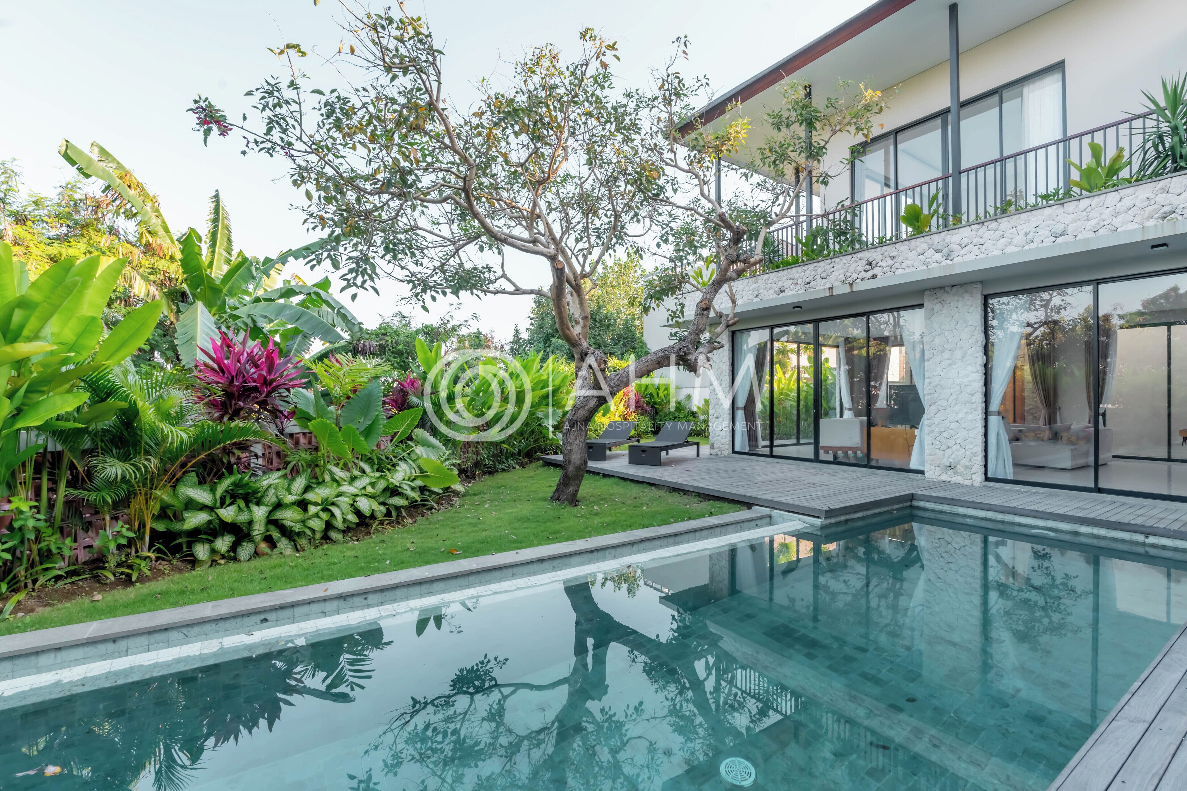 A modern house with a swimming pool, surrounded by lush greenery and a well-maintained garden.