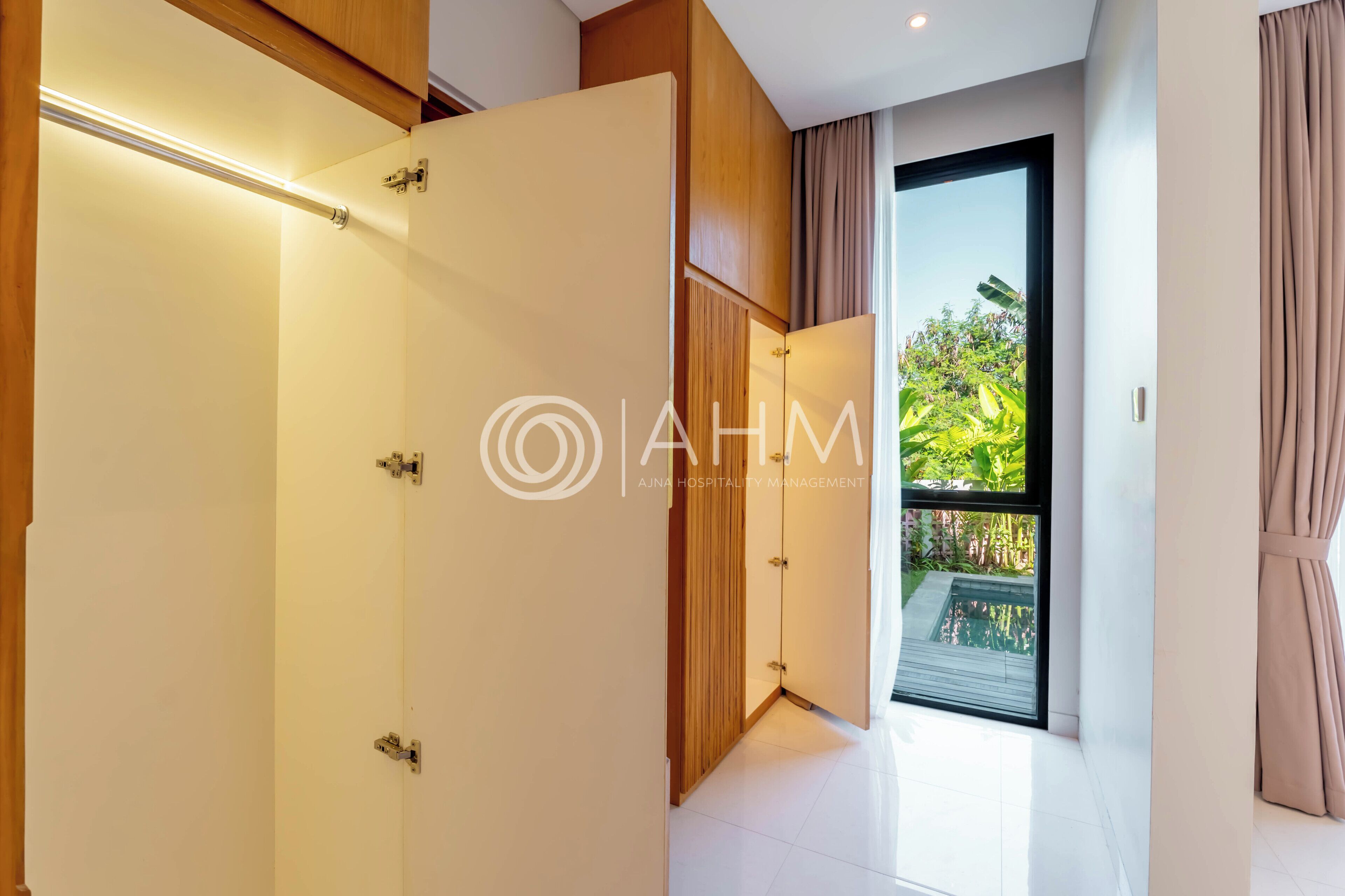 A modern hotel room with a large sliding door leading to a balcony with a pool view.