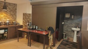 A kitchen with a dining table, chairs, a coffee station, and a sink. - Blue Poppy by Orangepetal (Gangtok)