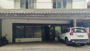 A white SUV parked in a covered parking area with a tiled floor and a decorative railing. - Blue Poppy by Orangepetal (Gangtok)