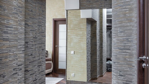 A hallway with stone walls, a wooden floor, and a door leading to another room. - Spacious apartment near railway station (Minsk)