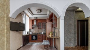 A modern kitchen with wooden cabinets, a built-in oven, and a small island with a sink. - Spacious apartment near railway station (Minsk)