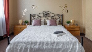 A neatly made bed with a fluffy white duvet, two bedside tables with lamps, and a decorative wall piece above the bed. - Spacious apartment near railway station (Minsk)