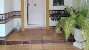 A clean entrance with a tiled floor, a white door with a yellow frame, and a window with a metal grille. - Semi-detached house - Los Boliches - Fuengirola (FUENGIROLA)