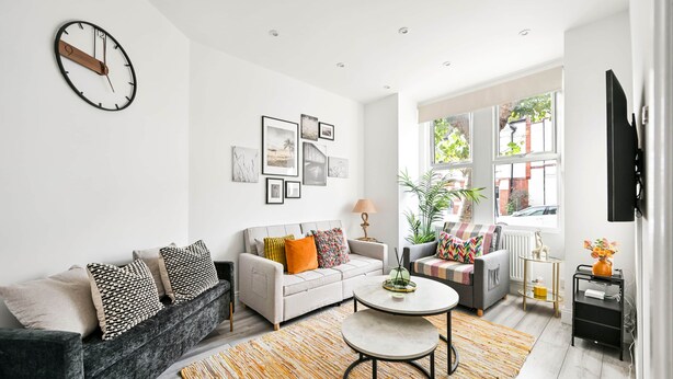 A modern living room with a sofa, coffee table, and a wall clock.