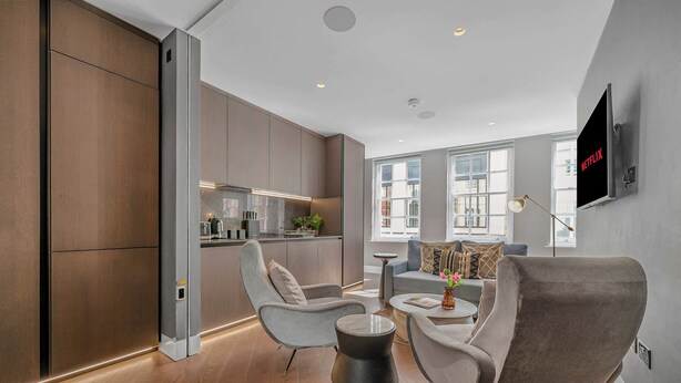 A modern living room with a grey sofa, a coffee table, and a TV mounted on the wall.