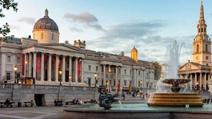 A historic building with classical architecture, a prominent fountain, and a statue.