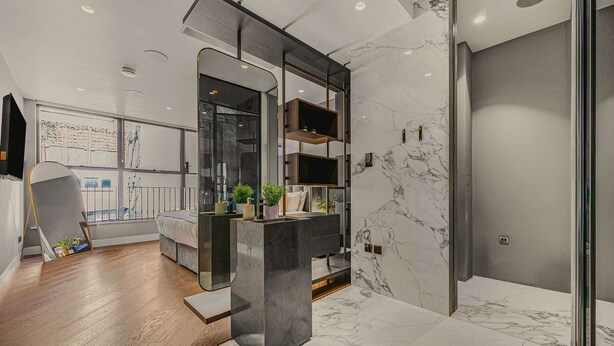 A modern bathroom with a marble floor, a large mirror, and a built-in shelf with plants.