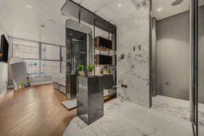 Un baño moderno con piso de mármol, un espejo grande y un estante empotrado con plantas.