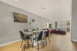 A modern dining area with a wooden table, black chairs, and a red sofa in the background. - Soho Mews Duplex · 2-Bed with AC · Sleeps 6 (London)