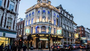 A historic theater with ornate architecture, a marquee, and a busy street scene.