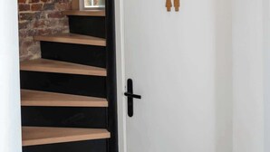 A staircase with black steps leading to a white door with a black handle. There are two wooden figures on the door.