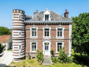 A large brick building with a central tower, multiple windows, and a front entrance.