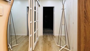 Un pasillo con suelo de madera, un televisor fijado a la pared y un perchero.