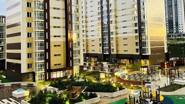 Un edificio residencial alto con varios balcones, un jardín en la azotea y un área de juegos.