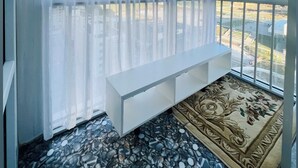 Una habitación con un ventanal grande, un banco blanco y un tapete estampado.