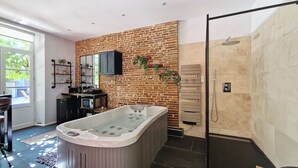 Un baño moderno con bañera, ducha y pared de ladrillo.