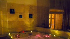 Un jacuzzi con velas, una ventana y una pared decorada con pequeños detalles cuadrados.