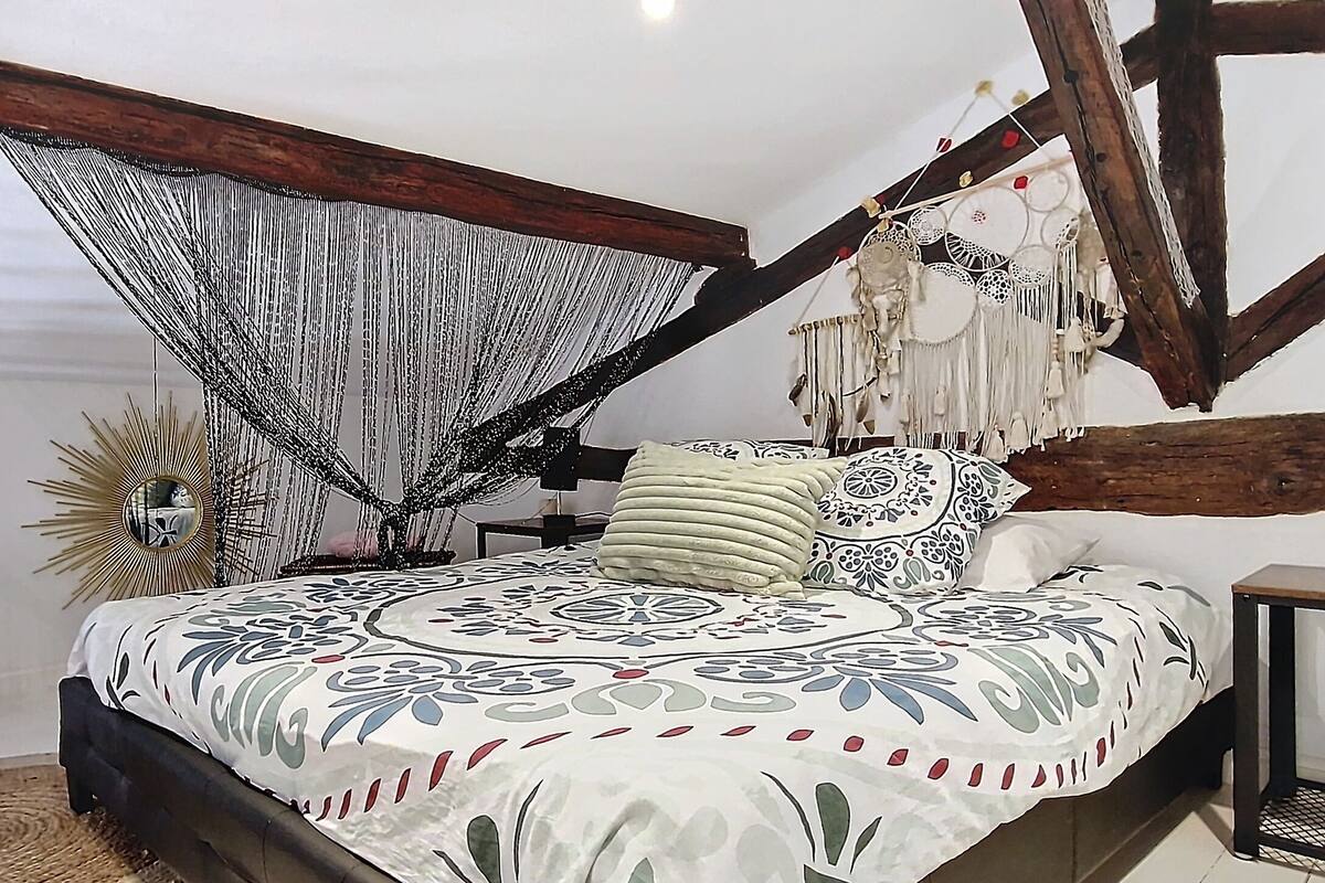 A bedroom with a bed, a hanging chair, a mirror, and a dreamcatcher.