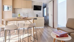 A modern kitchen with a central island, bar stools, a dining table, and a sofa. - Blendin Agde  (Agde)
