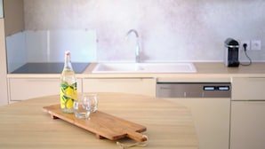 A kitchen with a wooden table, a bottle of water, and a glass. - Blendin Agde  (Agde)