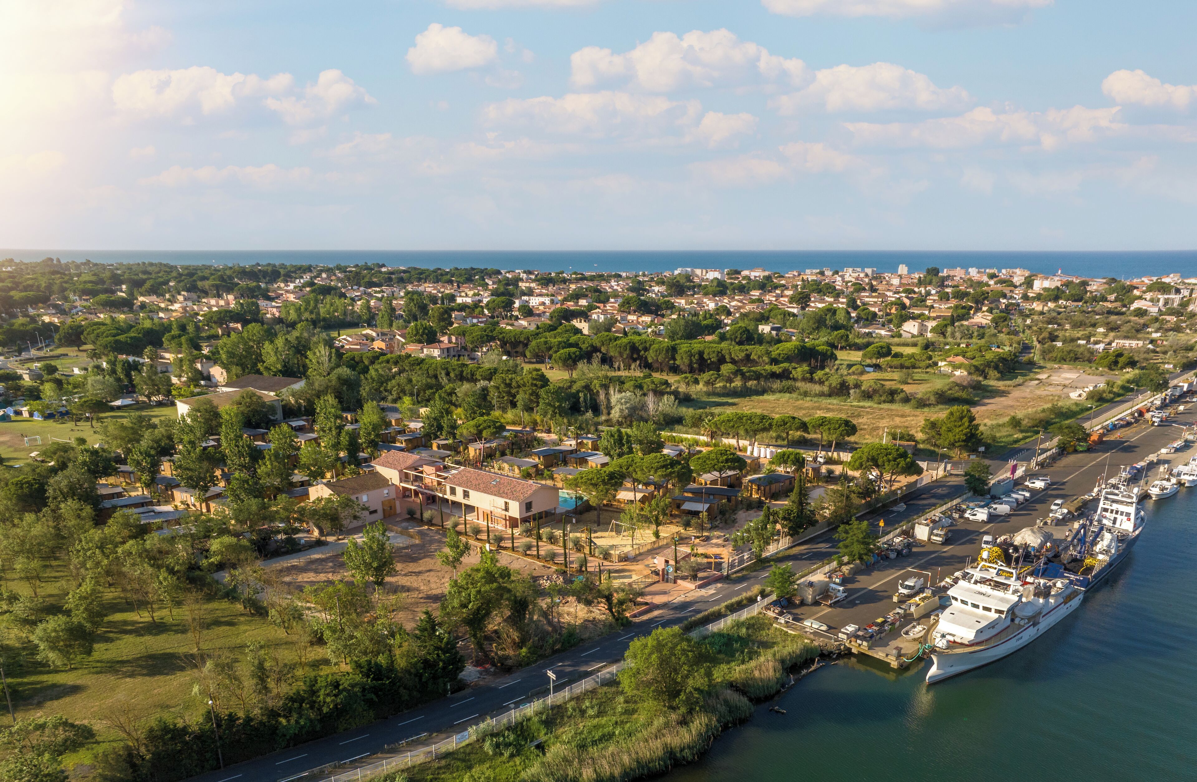 Luchtbeeld van een kustplaatsje met een jachthaven, woongebouwen en groene zones.