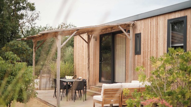 A wooden deck with outdoor furniture, a pergola, and a sliding glass door leading to a covered patio area. - Blendin Agde  (Agde)