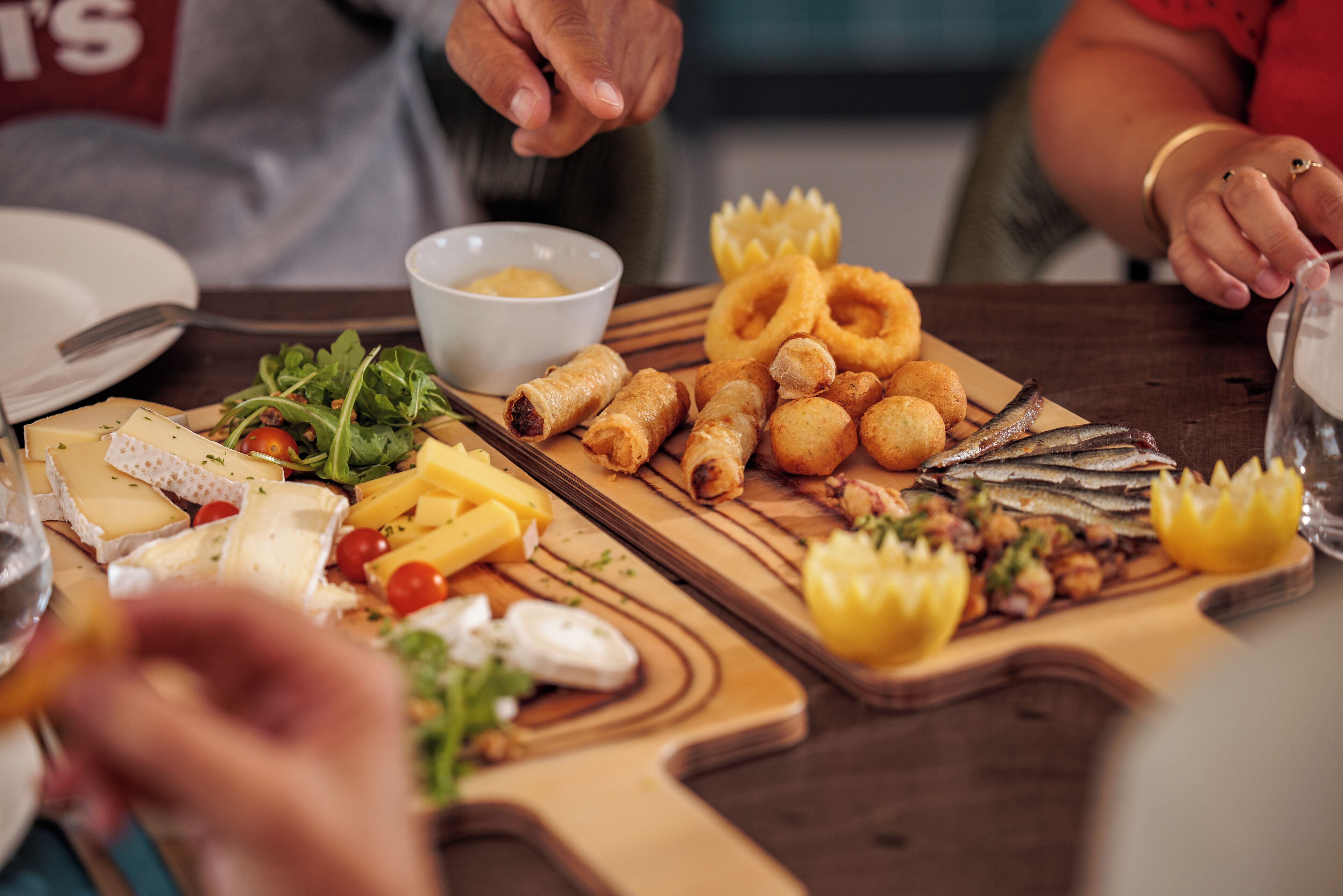A wooden table with various food items including cheese, salad, and seafood.