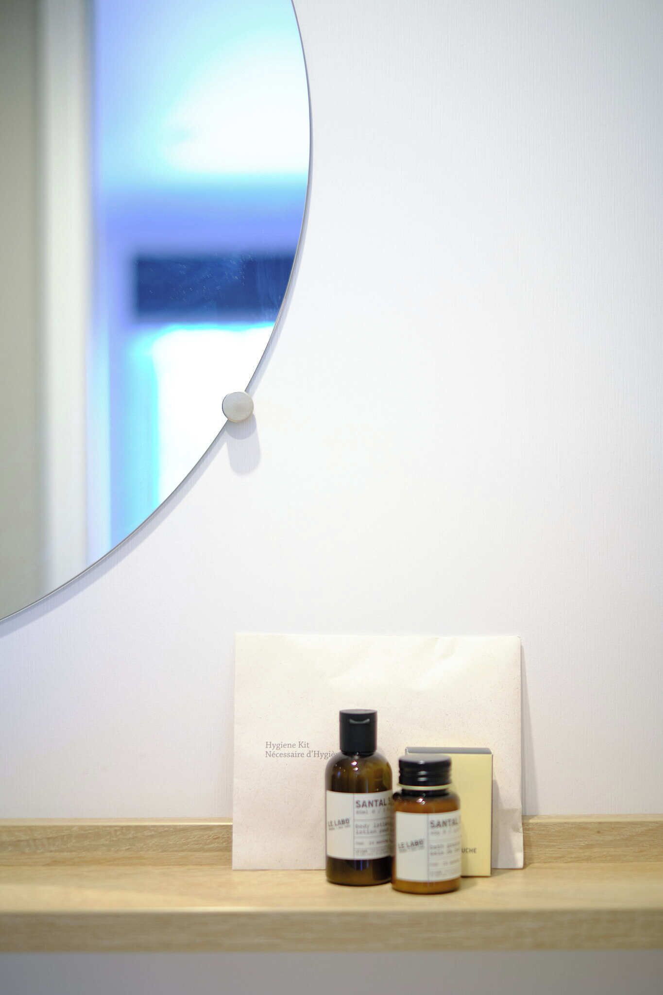 Une étagère de salle de bain avec un nécessaire d'hygiène et deux flacons étiquetés « SANTAL ».