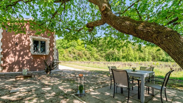 Un patio con mesa y sillas, una mesita con un bol, y una ventana.