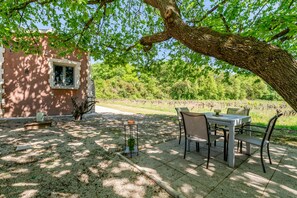 A patio with a table and chairs, a small table with a bowl, and a window. - La Petite Maison in the Vineyard (Gaujac)