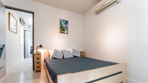 Un dormitorio moderno con una cama de madera, una mesita de noche con una lámpara, un reloj de pared y un cuadro enmarcado.