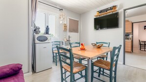 Una cocina moderna con una mesa de comedor, sillas, un refrigerador y un televisor.