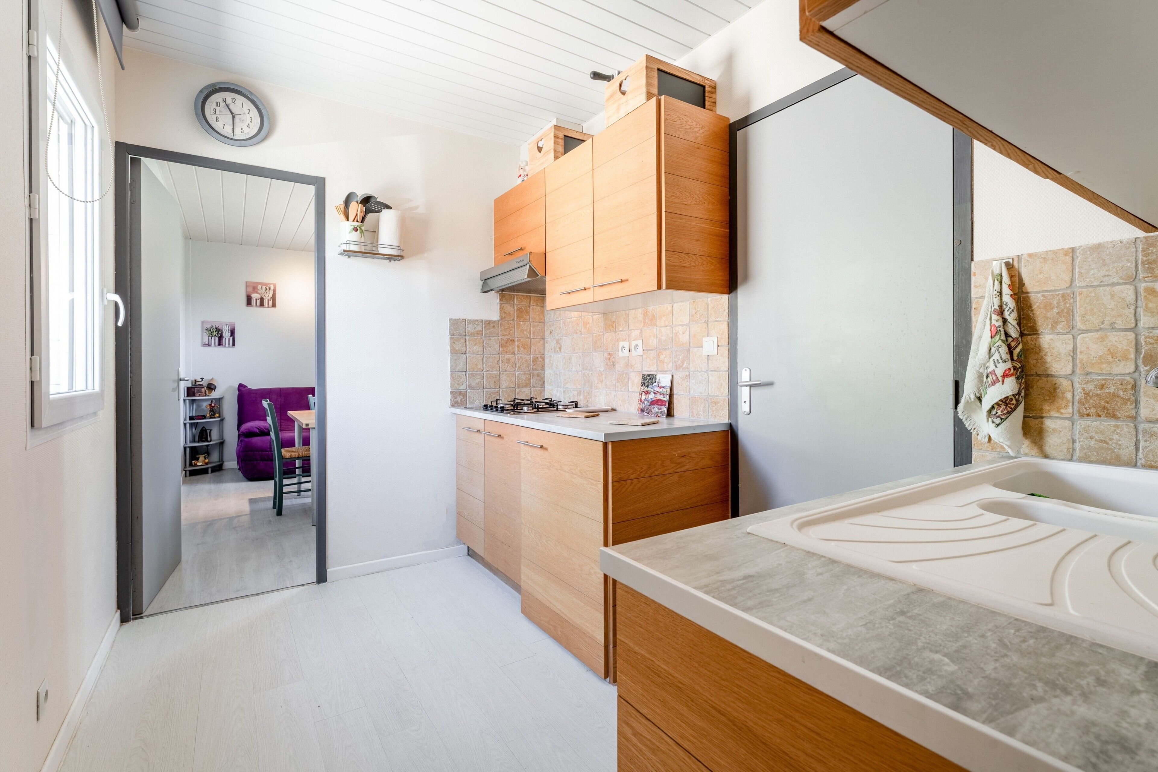 Une cuisine moderne avec des meubles en bois, un pare-feu en carrelage et un four encastré.