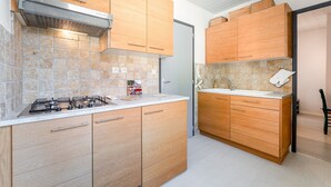 Una cocina moderna con armarios de madera, estufa a gas y salpicadero de azulejos.