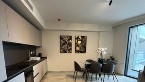 A modern kitchen with a dining area, featuring a large window and a view of the city.